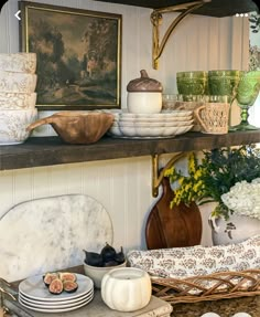 a shelf filled with plates and bowls on top of a counter next to vases