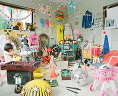 two people sitting at a table in front of a laptop computer surrounded by toys and other items