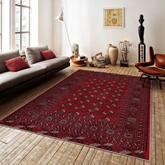 a living room filled with furniture and a red rug on top of a hard wood floor