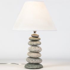 a lamp that is on top of some rocks and has a white shade over it