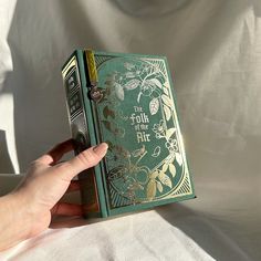 a hand is holding an old book in front of a white sheet that says the folk of the air