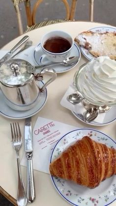 an assortment of pastries and coffee sit on a table with silverware, spoons and cups