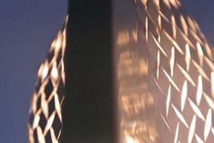 the side of a tall building with a clock on it's face and light reflecting off its windows