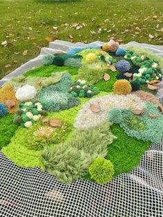 a large piece of art made out of grass and flowers on a mesh table cloth