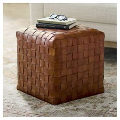 a brown leather ottoman with a book and glasses on top