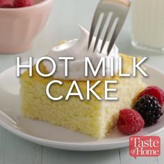 a white plate topped with a piece of cake next to raspberries and a glass of milk