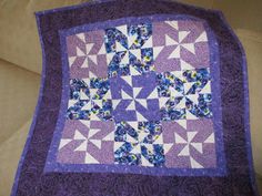 a purple and white quilt on the back of a couch