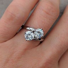 a woman's hand with two engagement rings on it