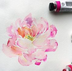 a watercolor painting of a pink flower on white paper with crayons next to it