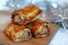 three pastries sitting on top of a wooden cutting board next to silver tinsel