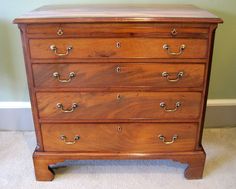 an old wooden dresser with brass handles and knobs on the bottom drawer, in front of a stone wall