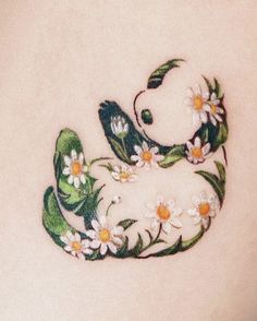 a small tattoo on the back of a woman's stomach with daisies and a teddy bear