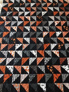 an orange and black quilt with triangles on it