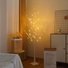 a lighted tree in the corner of a room next to a box with flowers on it