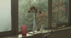 a window sill with two vases and a pink glass on top of it