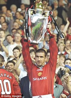 a man holding up a trophy above his head in front of a large group of people