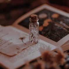 an open book sitting on top of a table next to a glass bottle filled with liquid