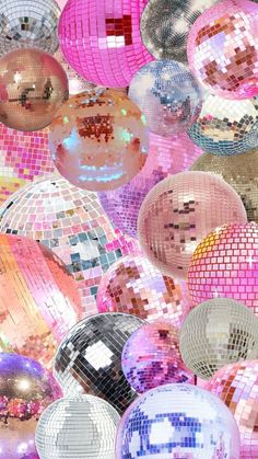 many shiny disco balls hanging from the ceiling in different colors and sizes, all grouped together