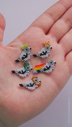 four small beaded birds sitting on top of a hand