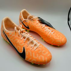 a pair of orange and black nike soccer cleats on top of a table