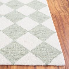 a white and green rug on top of a wooden floor