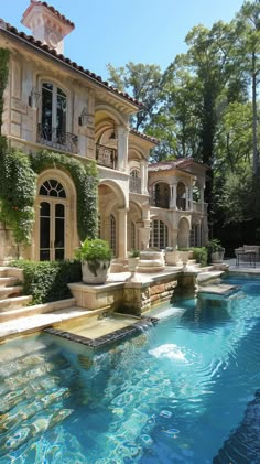 an outdoor swimming pool in front of a large house with steps leading up to it