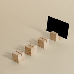 three pieces of wood are arranged in the shape of blocks, with one black piece on top