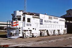 an electric locomotive sitting on the tracks in front of a building