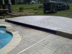 an empty swimming pool in the middle of a yard with a truck parked next to it