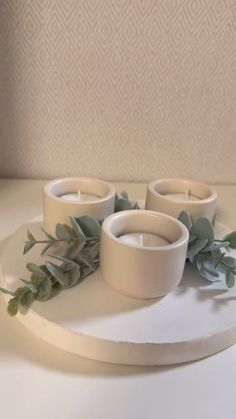 three candles are sitting on a tray with greenery