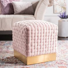 a living room area with a couch, chair and ottoman in pastel pink tones