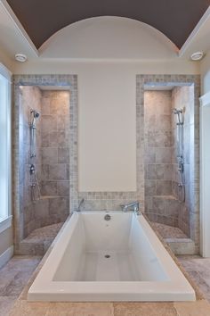 a large bath tub sitting in the middle of a bathroom next to two walk in shower stalls