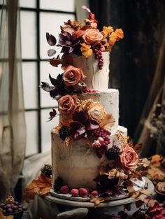 a three tiered cake with flowers and leaves on the top is surrounded by other decorations