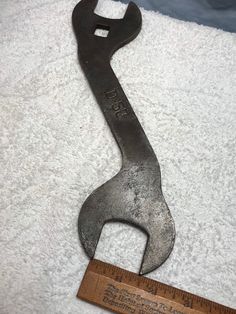 an old wrench sitting on top of a white towel with a ruler next to it