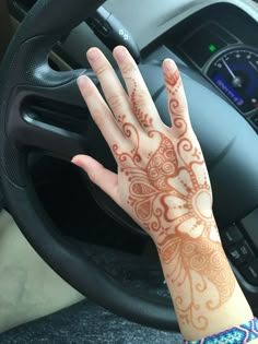 a woman's hand with hendix on it sitting in front of a steering wheel