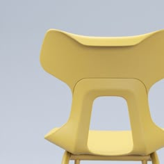 a yellow plastic chair against a gray background