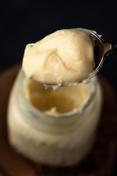 a spoon full of cream sitting on top of a jar