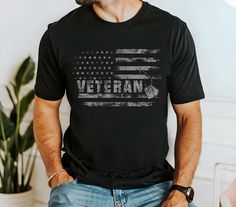 a man wearing a black shirt with an american flag on it and the words veteran written in white