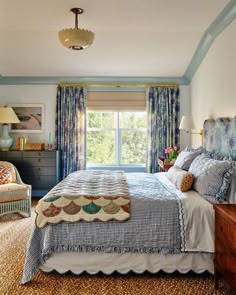 a bed sitting in a bedroom next to a window covered in blue and white curtains