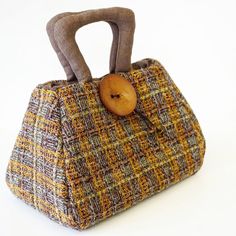 a handbag with a wooden button on the handle is shown in front of a white background