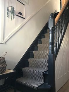 the stairs are lined with black and white striped rugs, along with a basket