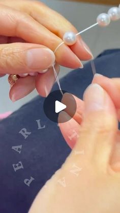 a woman is doing something with pearls on her fingers