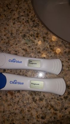 two white toothbrushes sitting on top of a counter next to a blue brush