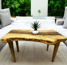 a wooden table sitting in the middle of a living room with white couches and pillows