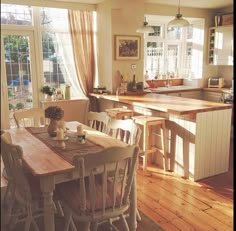 a kitchen with wooden floors and an island in the middle, surrounded by white chairs