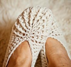 someone is wearing crocheted slippers with their feet on the carpet and they are both bare