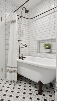 a white bath tub sitting next to a shower in a bathroom with black and white tile