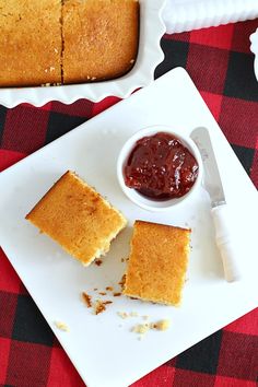 two pieces of cake sitting on top of a white plate next to a bowl of jam