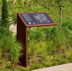 a wooden sign sitting in the middle of a lush green field