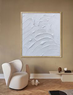 a white chair sitting in front of a painting on the wall